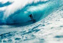 man riding surfboard in wavy ocean