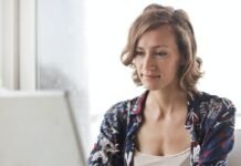 woman in blue floral top sitting while using laptop