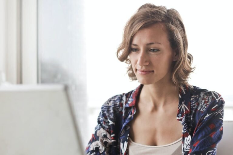 woman in blue floral top sitting while using laptop