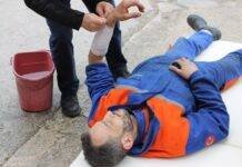 injured man lying on the ground receving a first aid treatment