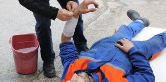 injured man lying on the ground receving a first aid treatment