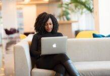 woman using macbook sitting on white couch