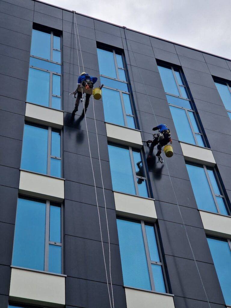 low angle shot of people cleaning the windows in a modern building in city