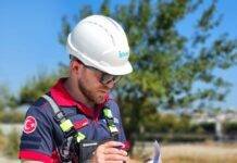 worker in helmet and vest with documents in hand