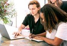 man working on laptop while woman takes notes