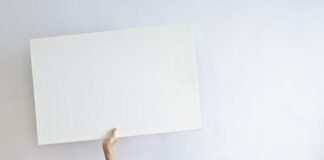 smiling ethnic woman with blank poster in empty flat