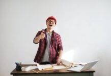laughing male constructor showing thumb up at working desk