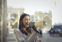 cheerful young woman screaming into megaphone