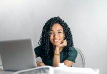 happy ethnic woman sitting at table with laptop