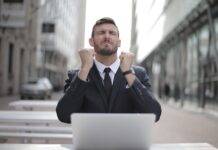 man in black suit sitting on chair beside buildings