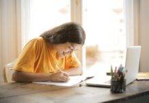 woman in yellow shirt writing on white paper