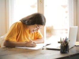woman in yellow shirt writing on white paper