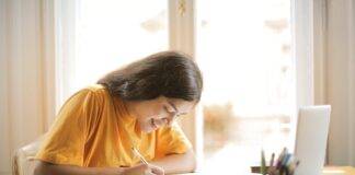 woman in yellow shirt writing on white paper