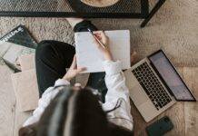 faceless lady with notebook and laptop on floor at home