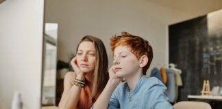 photo of woman and boy leaning on wooden table