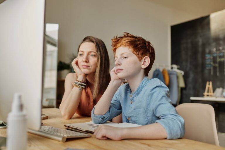 photo of woman and boy leaning on wooden table