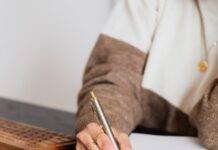 crop elegant business lady taking notes while sitting at desk