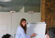employee drawing graph on flipchart during meeting in workspace