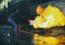 woman using fire extinguisher to eliminate fire