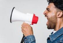 man in blue denim jacket holding a megaphone