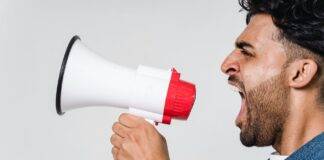 man in blue denim jacket holding a megaphone
