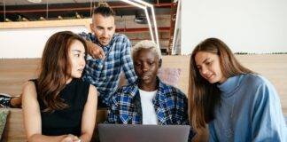 multiethnic coworkers watching plan on laptop