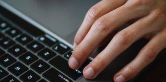 crop office worker typing on laptop at table