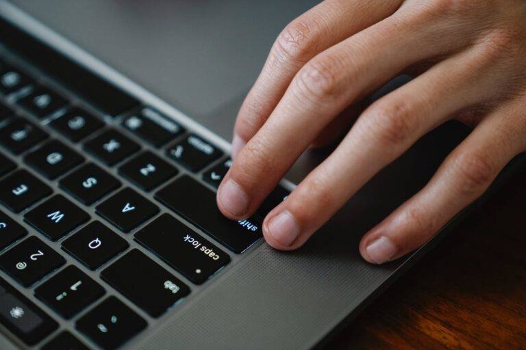 crop office worker typing on laptop at table