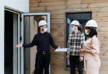 a man in black long sleeves talking to the couple while showing the house