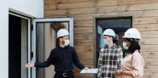 a man in black long sleeves talking to the couple while showing the house