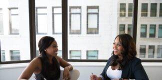 two woman in black sits on chair near table