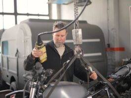 male mechanic using hydraulic crane in garage