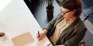 high angle photo of woman writing on notebook