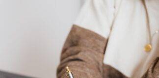 crop elegant business lady taking notes while sitting at desk