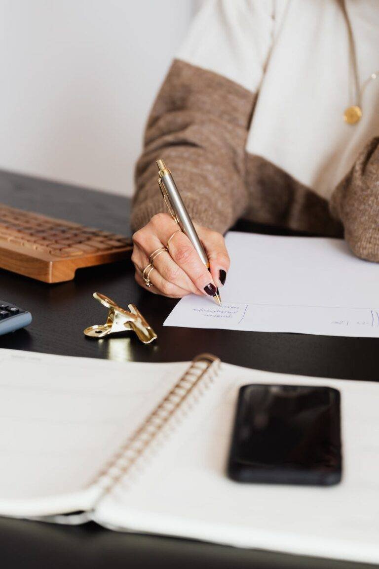 crop elegant business lady taking notes while sitting at desk