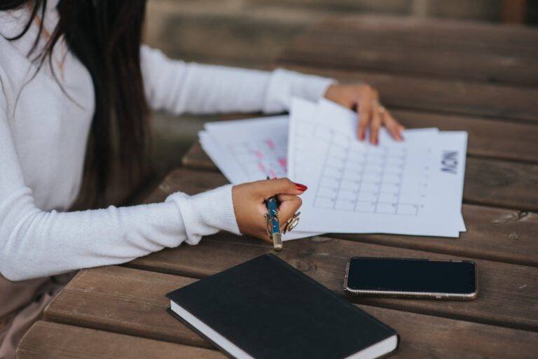 faceless ethnic worker making schedule at wooden table