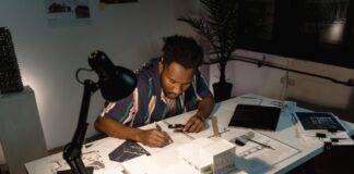 man writing notes on his work table