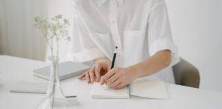 crop person writing in notebook at table