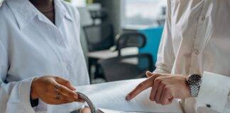 colleagues standing in white long sleeve shirts discussing and reading a financial report