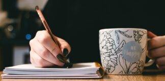 person holding white ceramci be happy painted mug