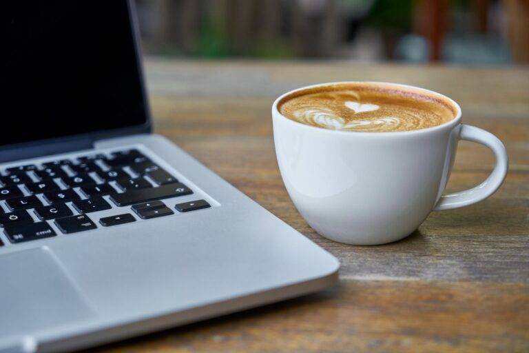 teacup of latte beside macbook pro