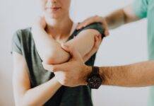 crop unrecognizable chiropractor examining arm joint of female patient
