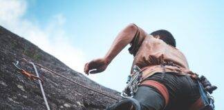 unrecognizable mountaineer climbing on cliff