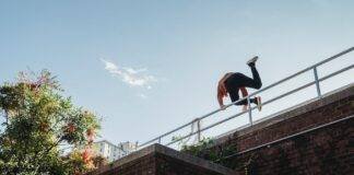 fearless unrecognizable man jumping over railing