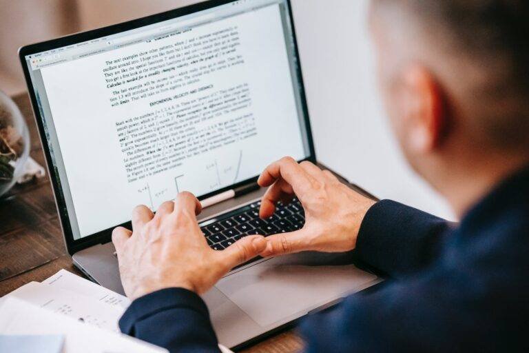 photo of person using laptop on wooden table