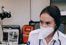 a woman wearing face mask while holding a patient s hand