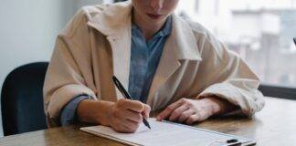 focused woman writing in clipboard while hiring candidate