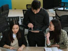 group of young people having a conversation in an office and man using a tablet