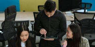 group of young people having a conversation in an office and man using a tablet