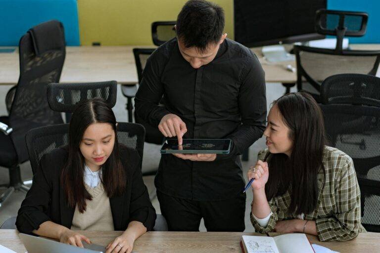 group of young people having a conversation in an office and man using a tablet
